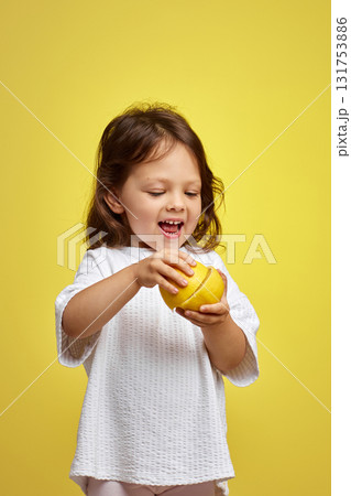 cute funny little child girl holding lemon on yellow background cute funny little child girl holding lemon on yellow background 131753886