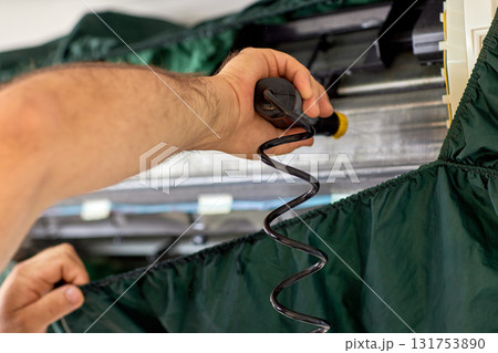 male hand of worker from the cleaning service cleans the air conditioner by spraying water, close-up 131753890