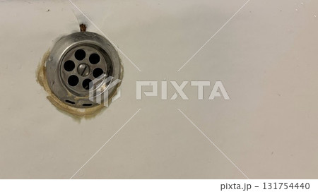 A close-up of an old bathtub drain against the background of old chipped enamel A close-up of an old bathtub drain against the background of old chipped enamel 131754440