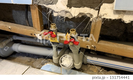 New plastic pipes with plugs in an apartment against the background of damaged tiles New plastic pipes with plugs in an apartment against the background of damaged tiles 131754441