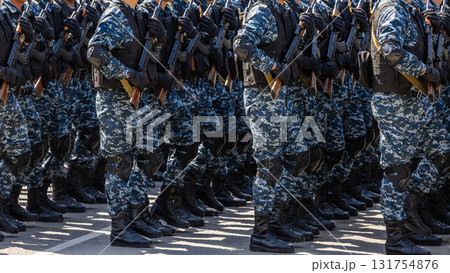 Many adult men marching in formation with assault rifles outdoors Many adult men marching in formation with assault rifles outdoors 131754876
