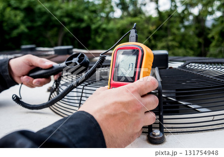 Technician use hand-held anemometer measuring air flowing measurement Technician use hand-held anemometer measuring air flowing measurement 131754948