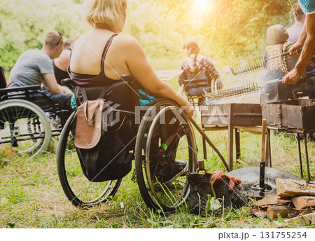 Disabled woman fries meat at the stake in a campsite with friends. Disabled woman fries meat at the stake in a campsite with friends. 131755254