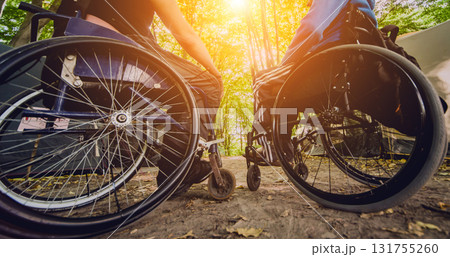 Two disabled men resting in a campsite with friends. Wheelchair in the forest  131755260