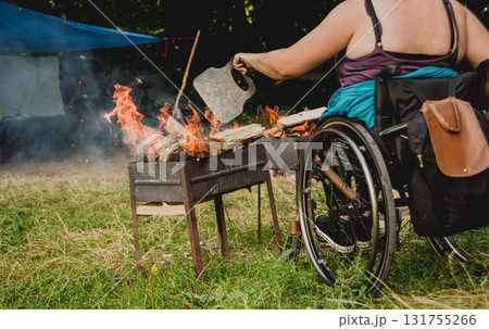 Disabled woman fries meat at the stake in a campsite with friends.  131755266