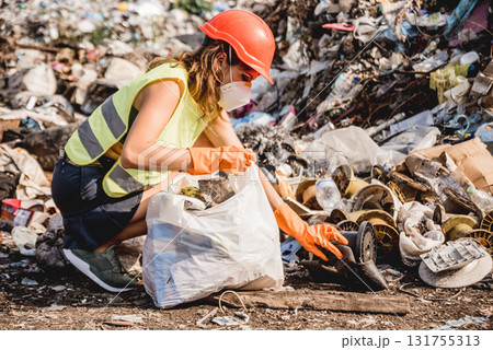 Woman volunteer helps clean the field of plastic garbage. Woman volunteer helps clean the field of plastic garbage. 131755313
