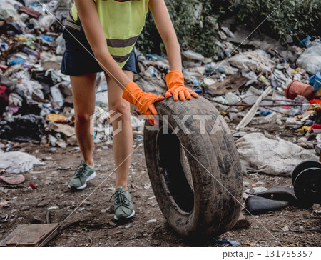 Woman volunteer helps clean the field of plastic garbage and old tires.  131755357
