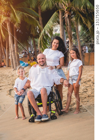 Disabled man in a wheelchair with his family on the beach. 131755650