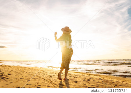 Beautiful woman at the windy spring day relaxing on coast. Carefree lady looking at the sunset. 131755724