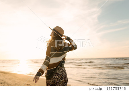 Portrait of a beautiful woman on the beach at sunset. Girl walks along the beach and enjoys weather Portrait of a beautiful woman on the beach at sunset. Girl walks along the beach and enjoys weather 131755746
