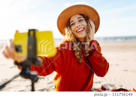 Happy woman using smartphone with stabilizer, live video in on sea beach. Live session blogging. 131756149