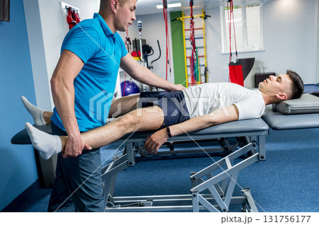 Rehabilitation therapy. Physiotherapist working with young male patient  131756177
