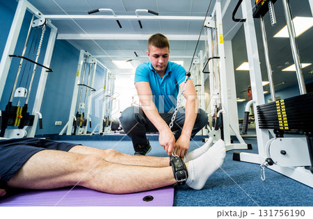 Rehabilitation therapy. Young man doing exercises on mat  131756190