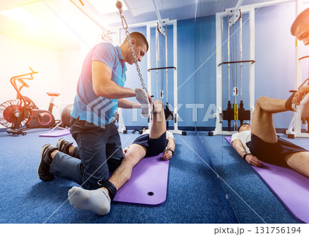 Rehabilitation therapy. Young man doing exercises on mat Rehabilitation therapy. Young man doing exercises on mat 131756194