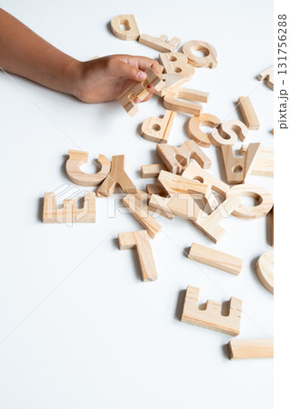 Child hand arranging wooden alphabet letters on white surface Child hand arranging wooden alphabet letters on white surface 131756288