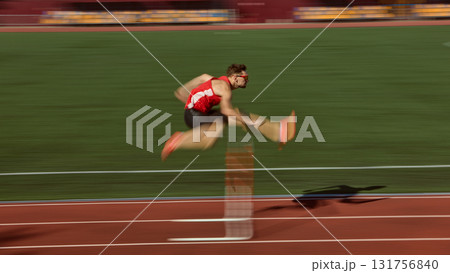 Hurdler in red sprinting and jumping over barrier with motion blur effect Hurdler in red sprinting and jumping over barrier with motion blur effect 131756840