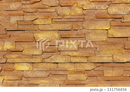 Close up of decorative stone fence made of rectangular textured stones in warm brown and golden tones, ideal for use in architecture, construction, and design backgrounds. Close up of decorative stone fence made of rectangular textured stones in warm brown and golden tones, ideal for use in architecture, construction, and design backgrounds. 131756856