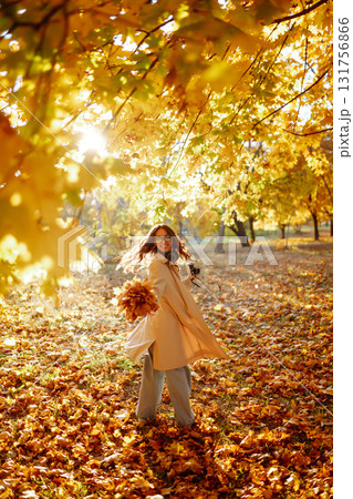 Young woman taking pictures in the autumn forest. Lady Walking In Fall Park With Yellow Foliage. Young woman taking pictures in the autumn forest. Lady Walking In Fall Park With Yellow Foliage. 131756866