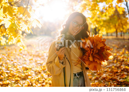Young woman taking pictures in the autumn forest. Lady Walking In Fall Park With Yellow Foliage. Young woman taking pictures in the autumn forest. Lady Walking In Fall Park With Yellow Foliage. 131756868