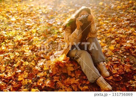 Young woman taking pictures in the autumn forest. Lady Walking In Fall Park With Yellow Foliage. Young woman taking pictures in the autumn forest. Lady Walking In Fall Park With Yellow Foliage. 131756869