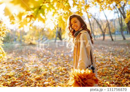 Young woman taking pictures in the autumn forest. Lady Walking In Fall Park With Yellow Foliage. 131756870