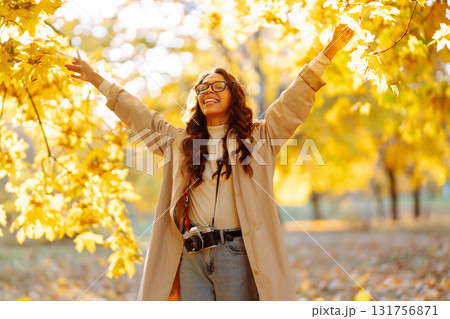 Young woman taking pictures in the autumn forest. Lady Walking In Fall Park With Yellow Foliage. 131756871