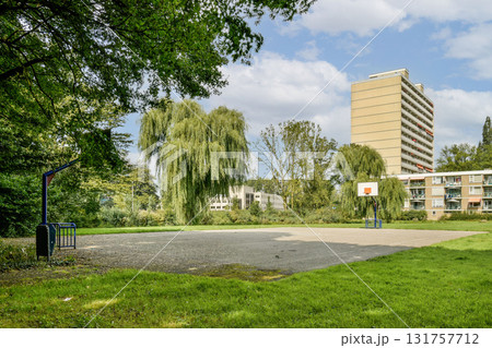 A spacious urban basketball court set amidst lush greenery and modern buildings, providing a vibrant recreational space for sports enthusiasts. A spacious urban basketball court set amidst lush greenery and modern buildings, providing a vibrant recreational space for sports enthusiasts. 131757712