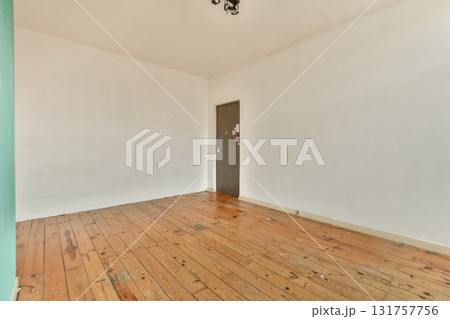 A spacious interior featuring wooden flooring and a plain wall with a door. The simplicity of the design creates a calm and inviting atmosphere. A spacious interior featuring wooden flooring and a plain wall with a door. The simplicity of the design creates a calm and inviting atmosphere. 131757756