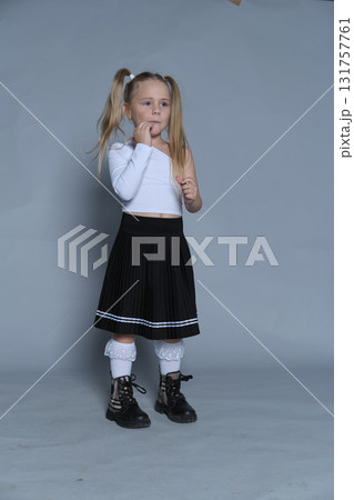 little girl stands in a fun and expressive pose, her fists playfully raised. The photo captures the energy and spontaneity of childhood, paired with her fashionable outfit. 131757761