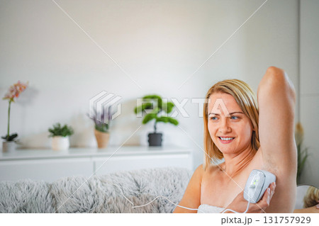 Smiling woman using an IPL device for hair removal at home 131757929