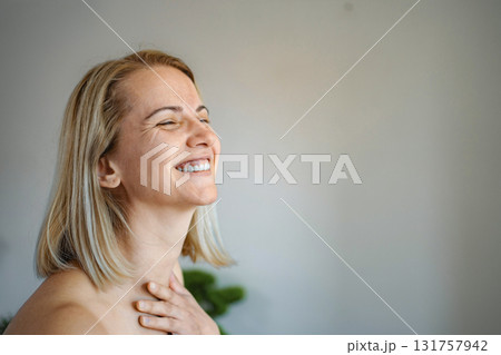 Happy blonde woman laughing with closed eyes and hand on chest 131757942