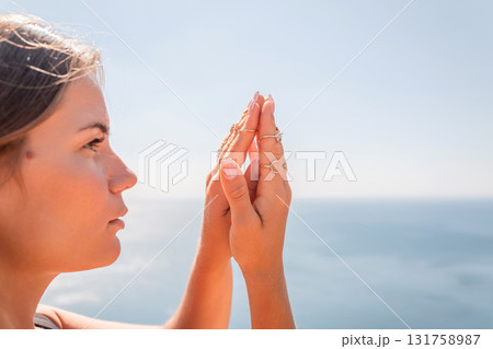 A woman with long hair is looking at the ocean A woman with long hair is looking at the ocean 131758987