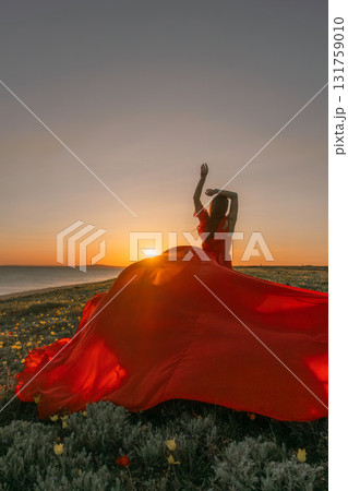 Sunset Dress Woman: Woman in red dress dances at sunset near sea, celebrating freedom, joy. Sunset Dress Woman: Woman in red dress dances at sunset near sea, celebrating freedom, joy. 131759010