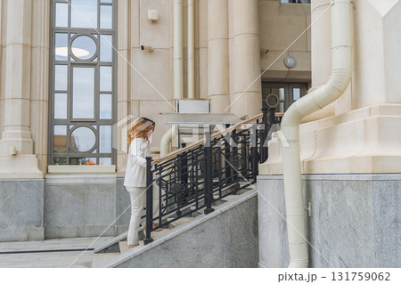 Woman, Stairs, Building - Woman descending stairs outside of a building with a large window. 131759062