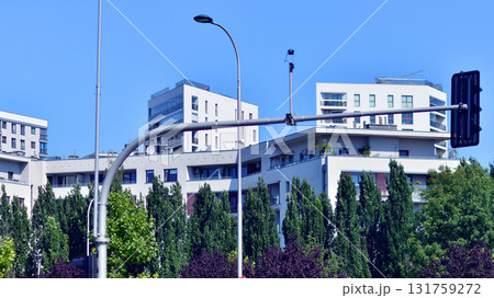 A residential building by lush green trees and surrounded by fresh vegetation on a clear sunny day. Modern architecture residential apartment building complex surrounded by greenery. A residential building by lush green trees and surrounded by fresh vegetation on a clear sunny day. Modern architecture residential apartment building complex surrounded by greenery. 131759272