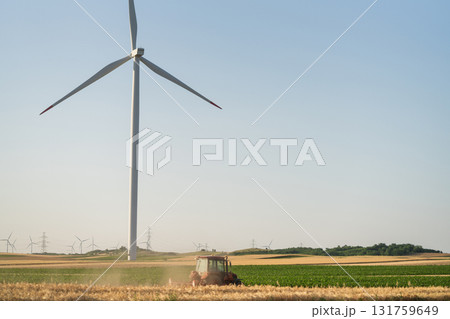 Agricultural tractor is working on the field with wind turbines Agricultural tractor is working on the field with wind turbines 131759649