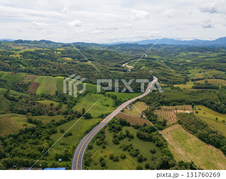 Aerial drone view of Highway winding through lush green mountains between Nan, Thailand. A scenic landscape of the road surrounded by tropical forest and a peaceful countryside 131760269