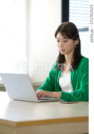 ノートパソコンで仕事をするオフィスカジュアルの女性 131762025