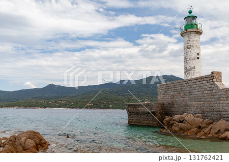 A sturdy stone jetty supports a classic lighthouse overlooking calm, clear waters 131762421
