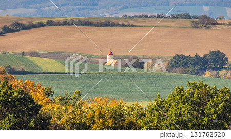 Rural landscape featuring rolling hills, cultivated fields, and a charming building with a red roof under the daylight. Moravia region of Czech Republic, Europe. Rural landscape featuring rolling hills, cultivated fields, and a charming building with a red roof under the daylight. Moravia region of Czech Republic, Europe. 131762520