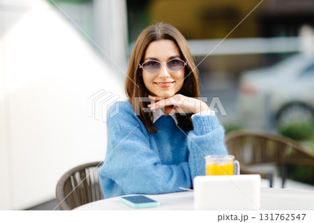 Young woman enjoying a relaxing moment at outdoor cafe 131762547