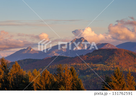 Mountainous landscape at dawn with warm sunlight illuminating forests and clouds, creating a peaceful view. The Mala Fatra national park in Slovakia, Europe. 131762591