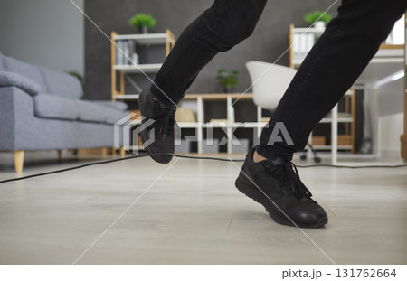 Closeup of feet of a person who trips over an electric cord at home or in the office 131762664