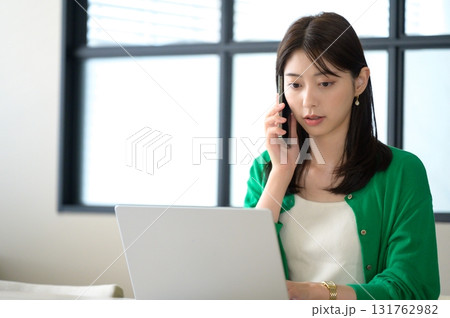 パソコンを操作しながら通話をする女性 パソコンを操作しながら通話をする女性 131762982