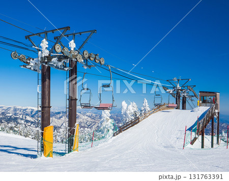 ゲレンデに設置されたリフトの中間降車プラットフォームと冬の山並み (群馬県、渋峠) 131763391