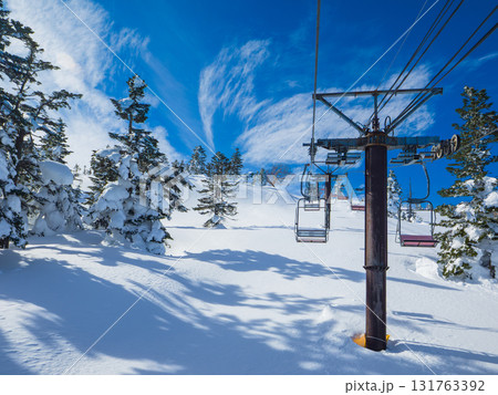新雪の斜面に落ちる木々の影と特徴的な雲が広がる空 (群馬県、渋峠) 131763392