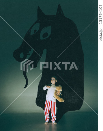 Modern composition. Little boy holding teddy bear standing before giant monster shadow with snake tongue Modern composition. Little boy holding teddy bear standing before giant monster shadow with snake tongue 131764105