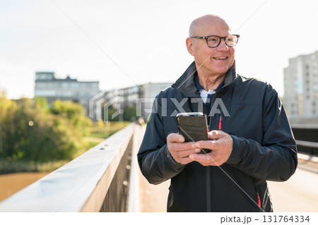 Portrait of senior man using mobile phone while standing on the bridge Portrait of senior man using mobile phone while standing on the bridge 131764334