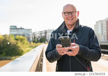 Portrait of senior man using mobile phone while standing on the bridge Portrait of senior man using mobile phone while standing on the bridge 131764335