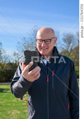 Senior man in sportswear using mobile phone while exercising in the park 131764350